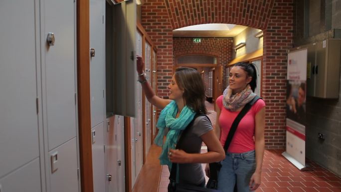 两个学生走在大学走廊的储物柜前