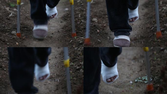 实拍一只脚受伤的人拄拐杖行走在小路田埂上