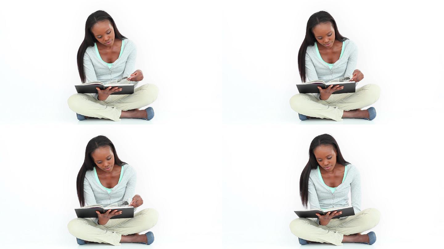 一个女人在白色的背景下交叉着双腿看书