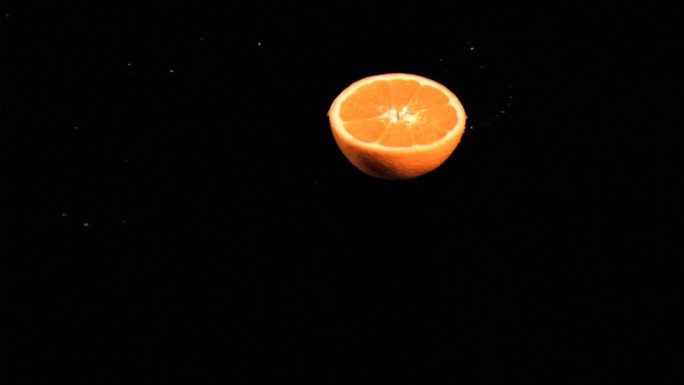 半个橙子在黑色背景下旋转特写