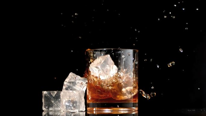 三个冰块掉入威士忌杯中特写