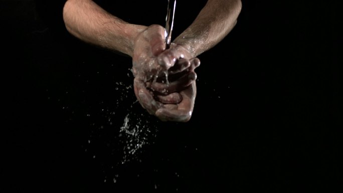 黑色背景下一个人在水中洗手特写