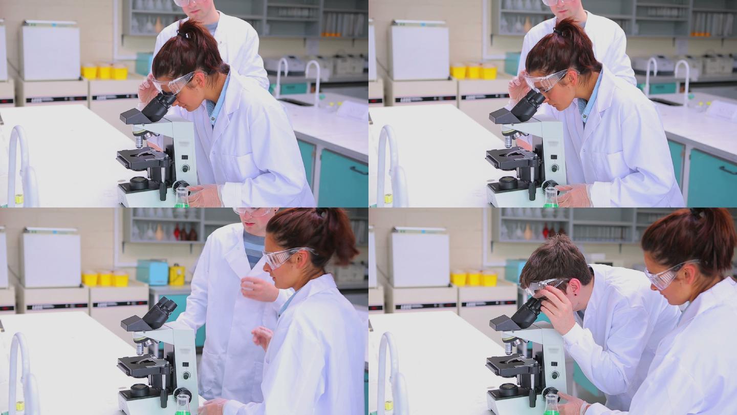 在实验室用显微镜做研究的学生