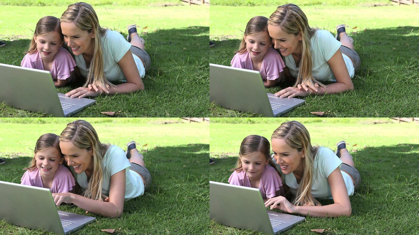 母亲陪女儿在公园看电脑特写
