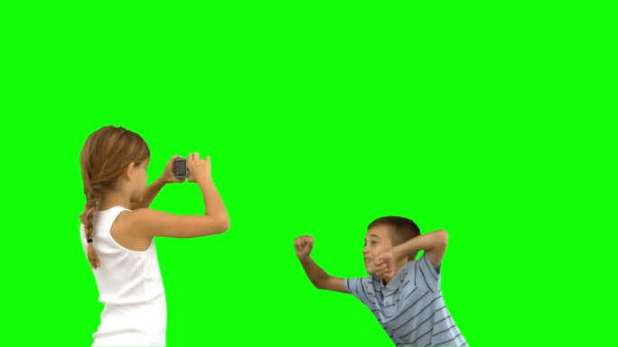 妹妹在绿色屏幕上用慢镜头拍摄弟弟的跳跃