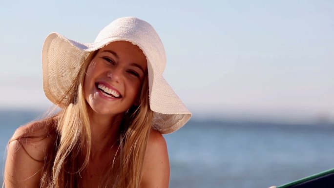 在阳光明媚的海滩上，一个可爱的女人在吊床上微笑着