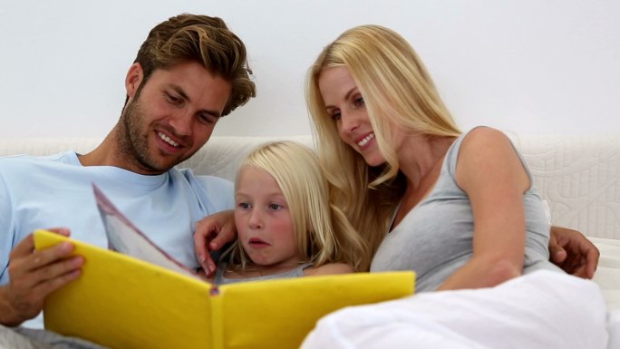 父母和女儿一起在家里的床上看书