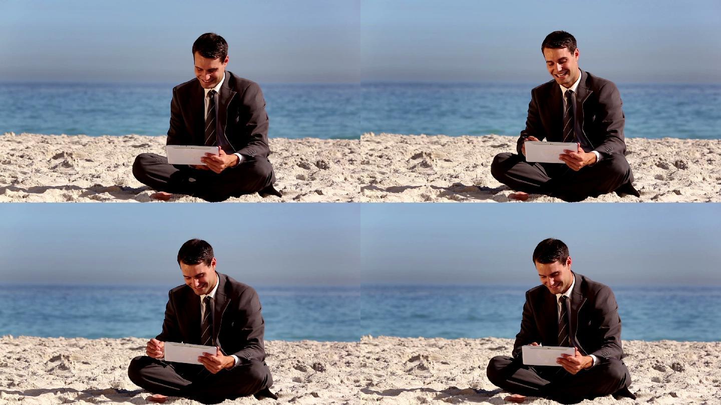 商人坐在沙滩上看平板电脑特写