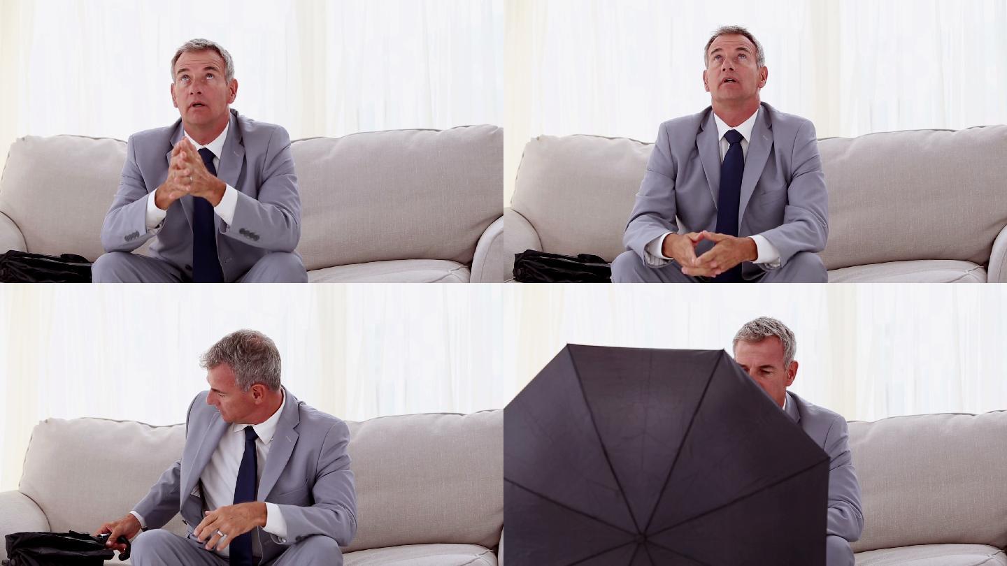 商人坐在沙发上打开伞在白色的背景