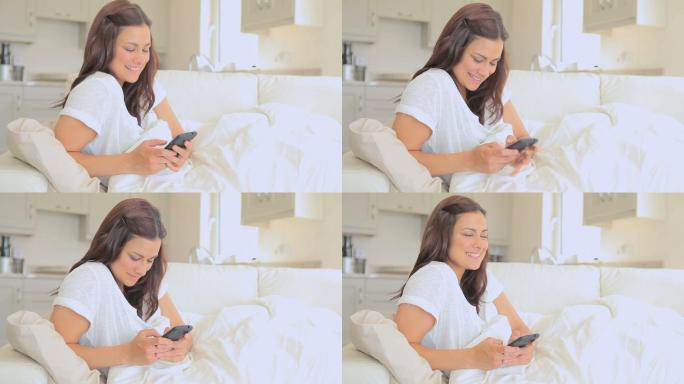躺在床上，微笑的女人用手机发短信