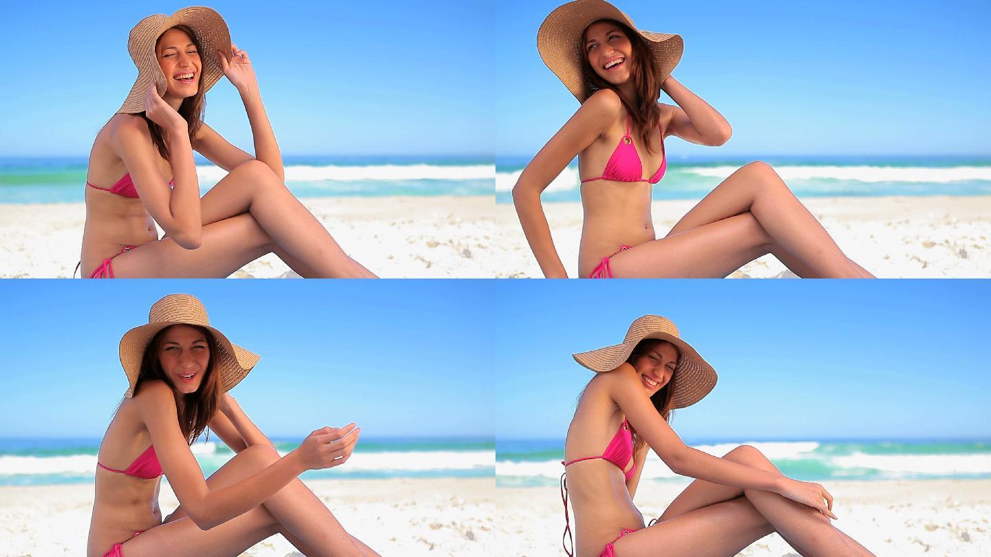 女人穿着比基尼坐在沙滩边注视镜头特写