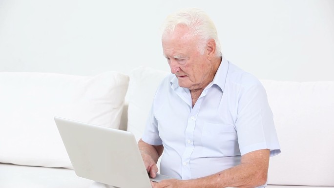 一个老人在客厅里用笔记本电脑