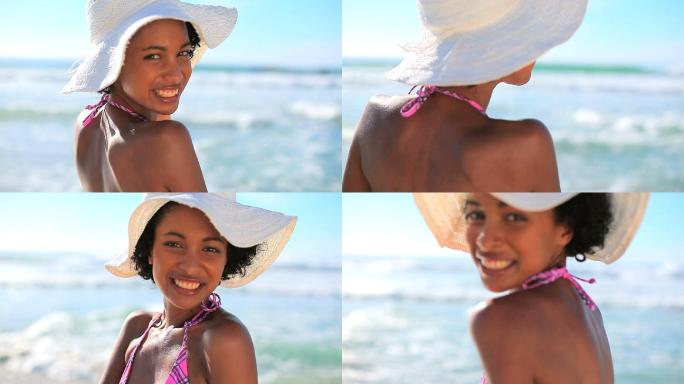 快乐的褐发女人戴着一顶草帽在海滩