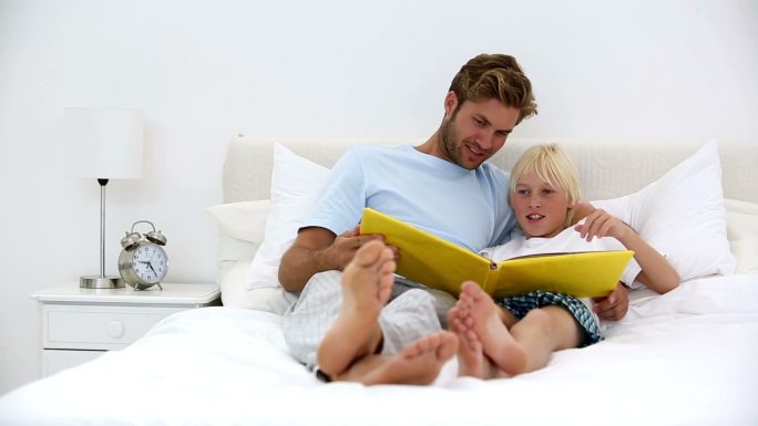 父亲和儿子一起在家里的床上看书