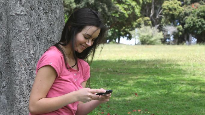 一个女人在公园里拿着手机特写