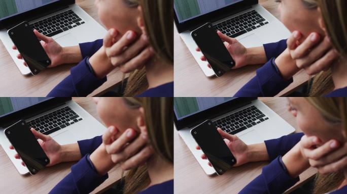 白人女性坐在办公室的桌子上使用智能手机和复印空间