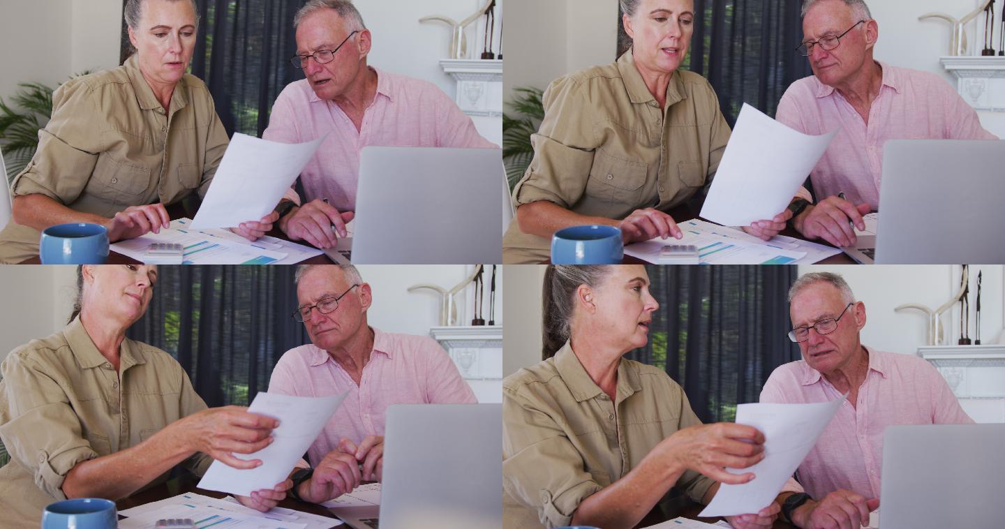 白种老年夫妇在家里用笔记本电脑计算财务