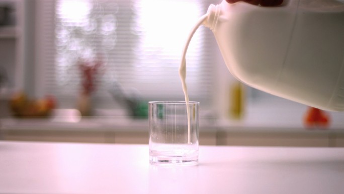 将牛奶倒入厨房的小玻璃杯中特写