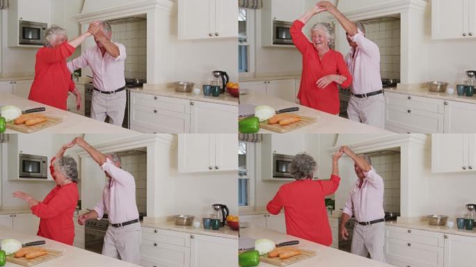 快乐的白种人老夫妇有乐趣在厨房跳舞，同时准备晚餐