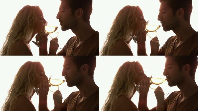 在慢镜头中，一对夫妇在阳光下交叉双臂一起喝酒