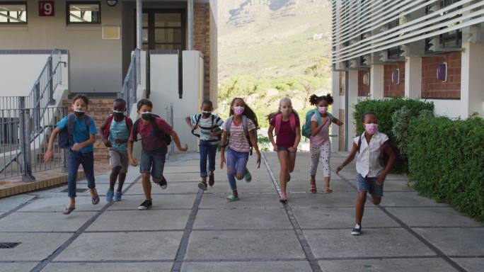 背着书包、戴着口罩的学童在校园奔跑