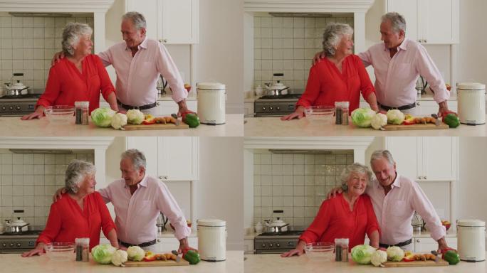 白人老年夫妇在家里的厨房里互相拥抱的画像