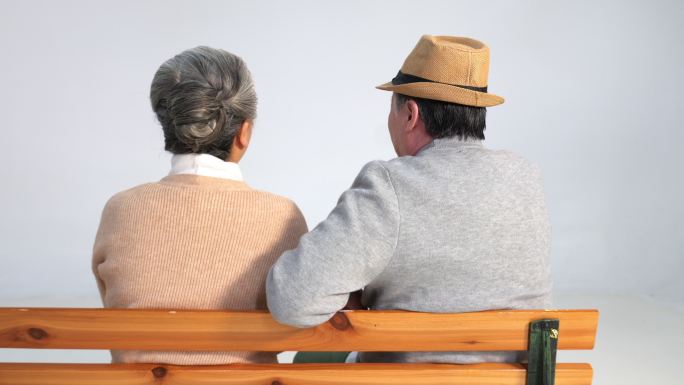 坐在长椅上聊天的老年夫妇背影