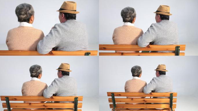 坐在长椅上聊天的老年夫妇背影