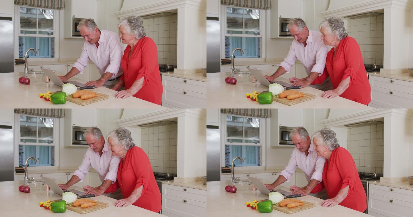 快乐的白种人老夫妇在厨房使用笔记本电脑的食谱准备饭前