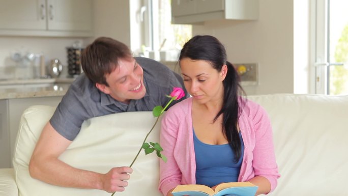 在沙发上看书的女人被丈夫拿着花惊呆了