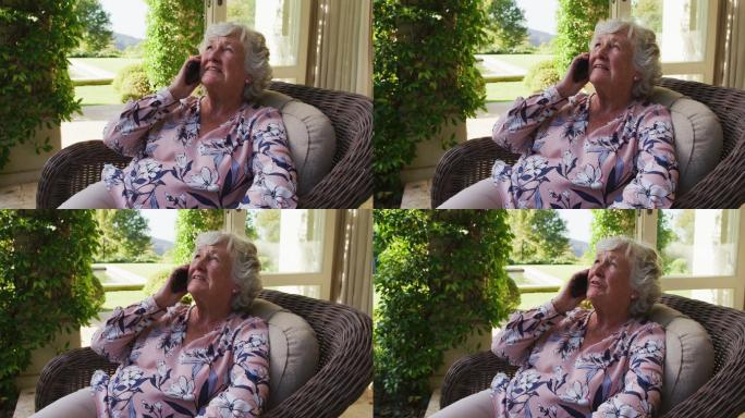白人老年女性坐在户外的椅子上用智能手机聊天