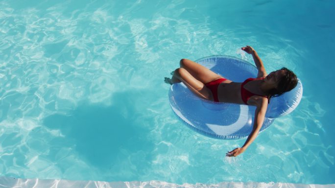 混合种族妇女有乐趣日光浴充气游泳池