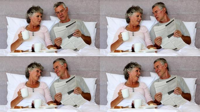 丈夫边吃早饭边给妻子读报纸