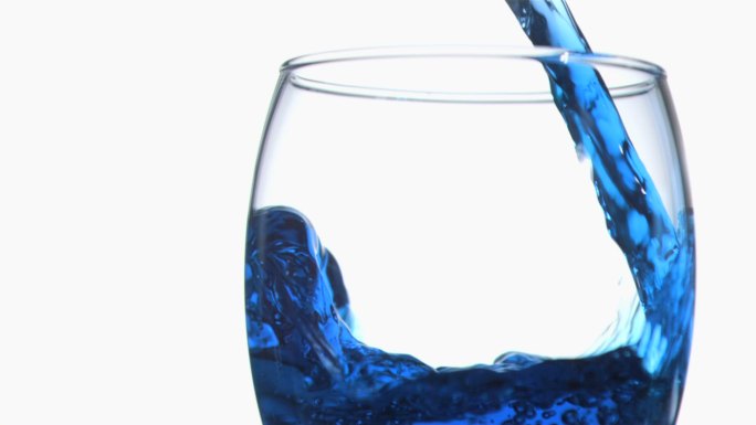 将蓝色液体倒入玻璃杯中特写