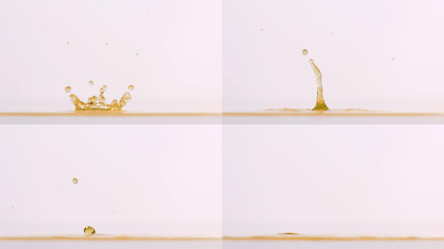 绿色液滴在黄色液体中以超慢的运动下落，背景是白色