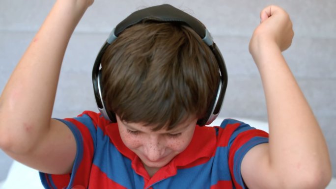 小男孩戴着耳机，以每秒250帧的慢动作欣赏音乐