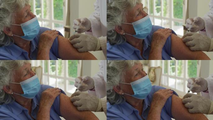 戴着口罩在家给老年女性注射新型冠状病毒疫苗的白人男医生