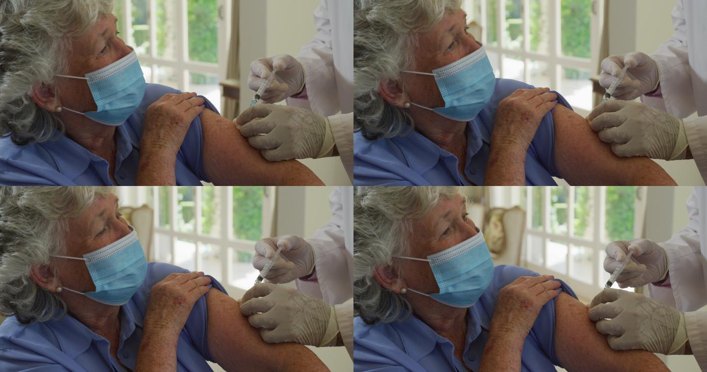 戴着口罩在家给老年女性注射新型冠状病毒疫苗的白人男医生