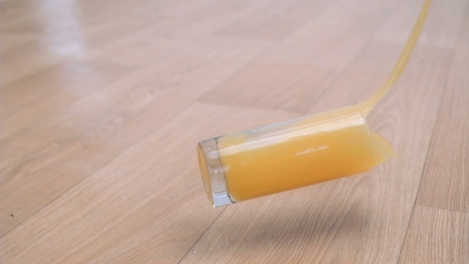 一杯超慢镜头的橙汁掉在地板上