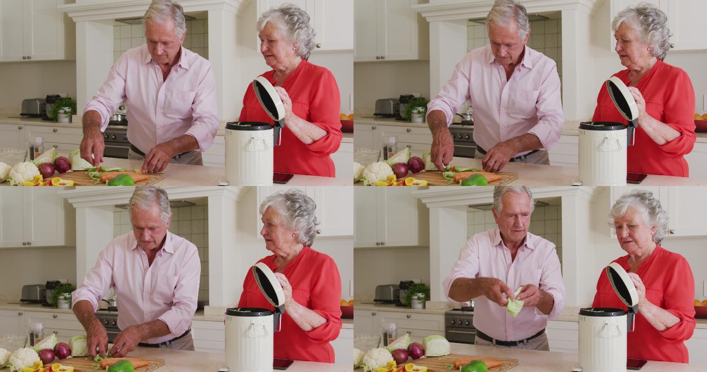 快乐的白人老年夫妇在厨房准备饭菜，堆肥蔬菜残渣