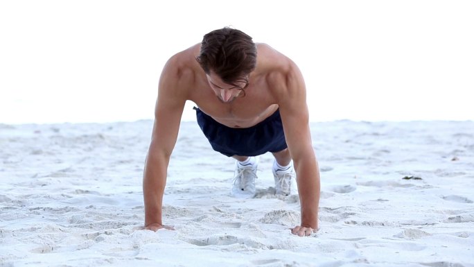 一个男人在海滩上做俯卧撑特写