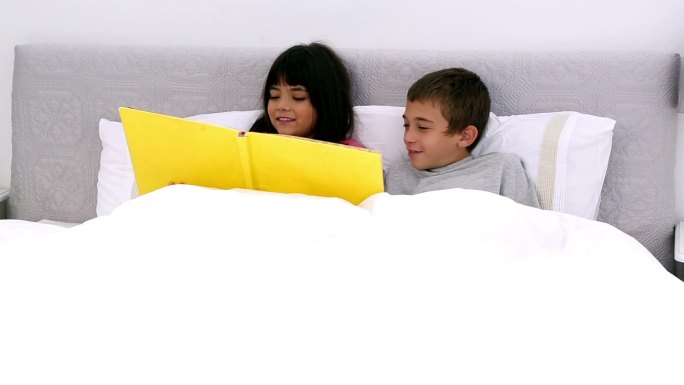 两个孩子在床上读故事