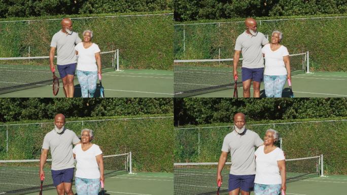 一对非洲裔美国老年夫妇拿着球拍在网球场上行走