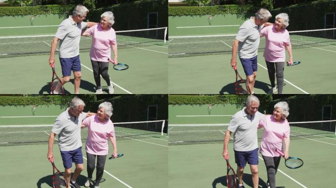 快乐的白人老年夫妇在户外网球场拥抱在阳光下打了一场比赛后