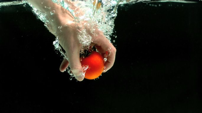 人的手从水中拿走西红柿特写