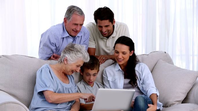 一个大家庭一起在家里的沙发上使用笔记本电脑