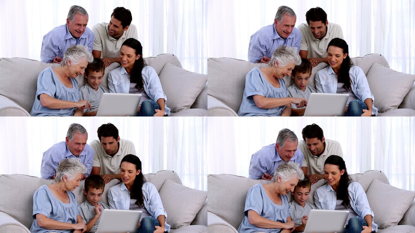 一个大家庭一起在家里的沙发上使用笔记本电脑