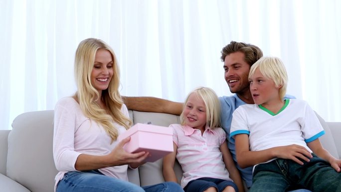 家人给妈妈一个粉红色的礼物，就是在家沙发上的一条围巾