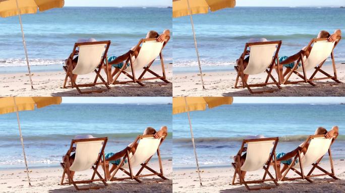 一对夫妇躺在沙滩的长椅上特写