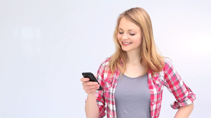年轻的金发女子在白色背景下展示智能手机屏幕